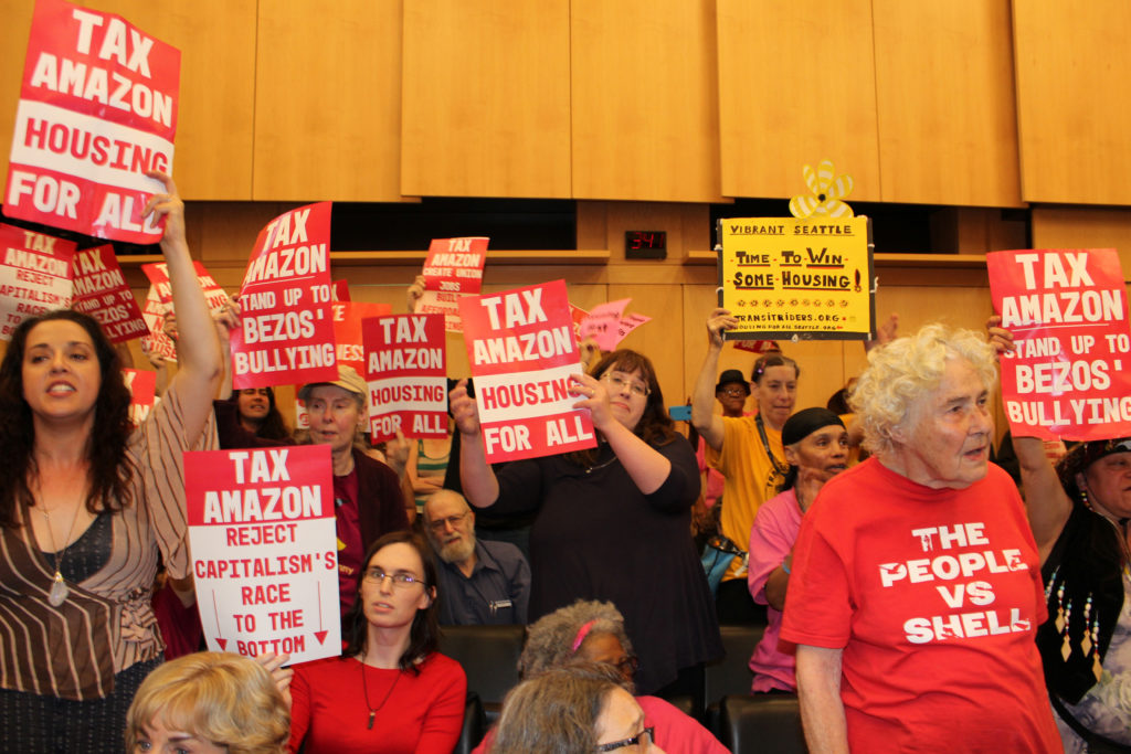 Protesters hold placards during a city council vote for a new "head tax" in Seattle